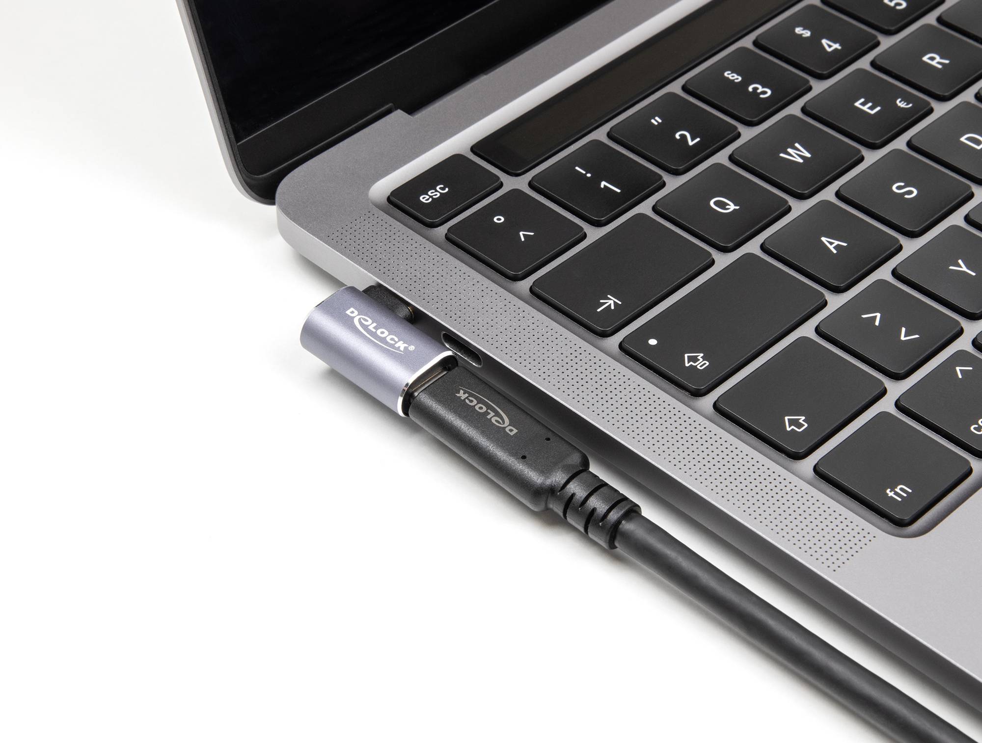 Ein Laptop mit einer schwarzen Tastatur; ein USB-Stecker ist in einen Anschluss eingesteckt.
