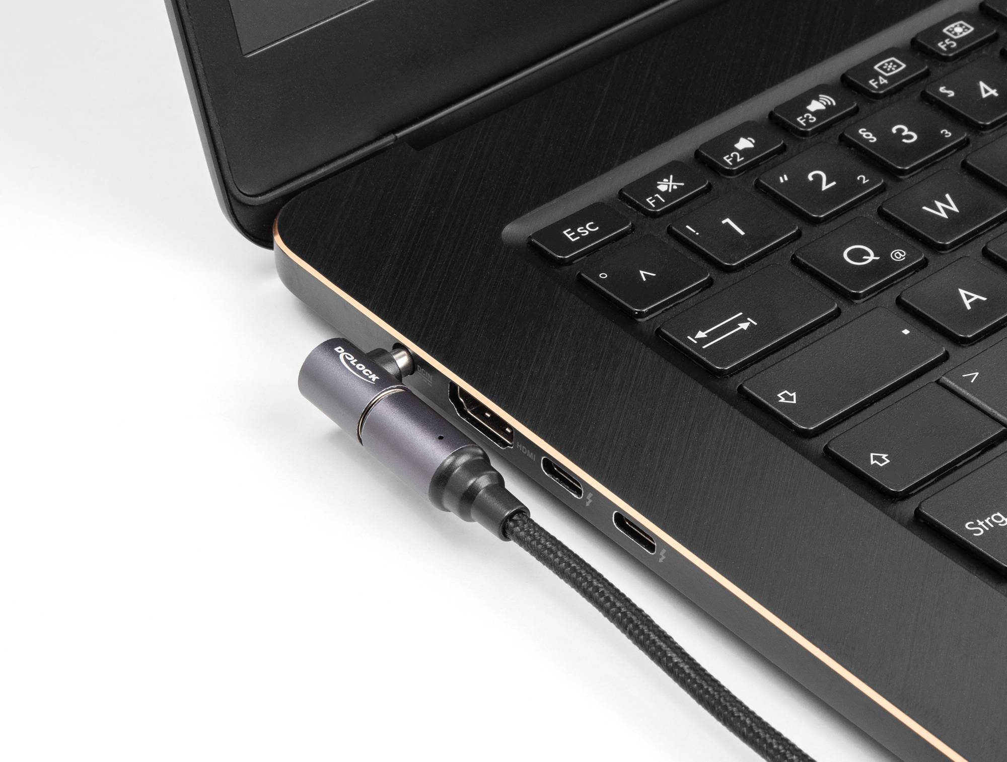 Ein Laptop mit schwarzer Tastatur aus der Nähe. Ein USB-Kabel ist in die linke seitliche Buchse des Laptops eingesteckt.