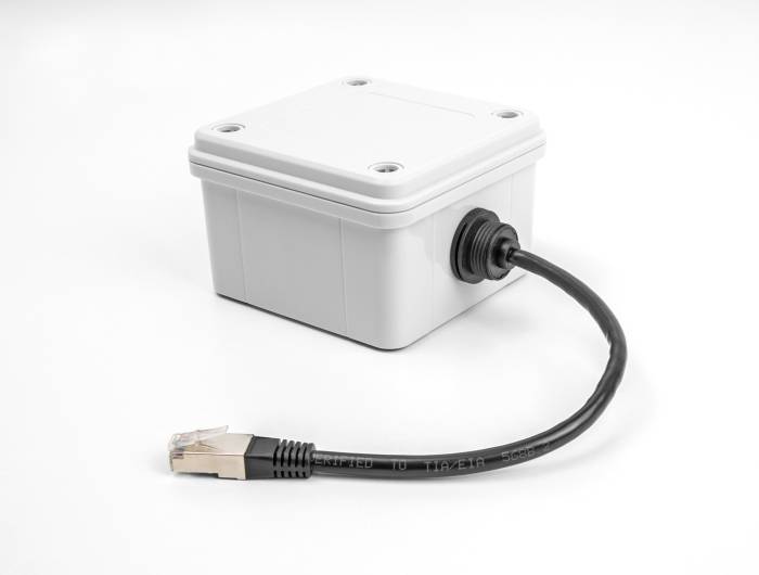 Eine graue, rechteckige Elektrokasten mit einem angeschlossenen Ethernet-Kabel, das für den Netzanschluss genutzt wird.
