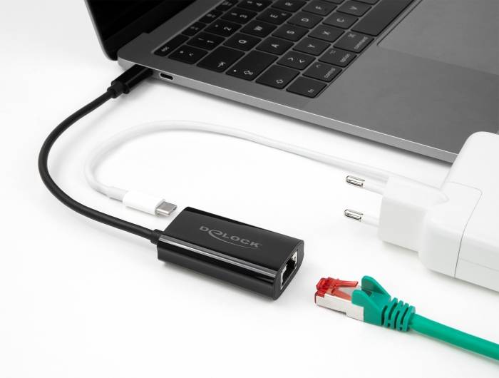 Ein Laptop ist mit einem Ethernet-Adapter verbunden. Ein Netzwerkkabel und ein Ladegerät liegen daneben.