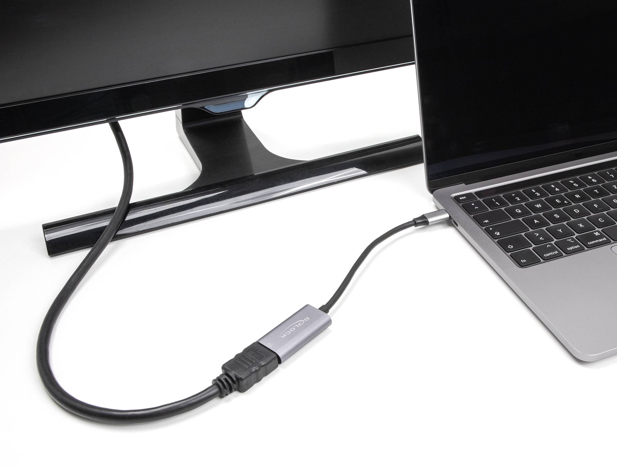 Ein HDMI-Kabel verbindet einen Laptop mit einem Monitor. Der Laptop ist auf der rechten Seite, der Monitor auf der linken Seite.