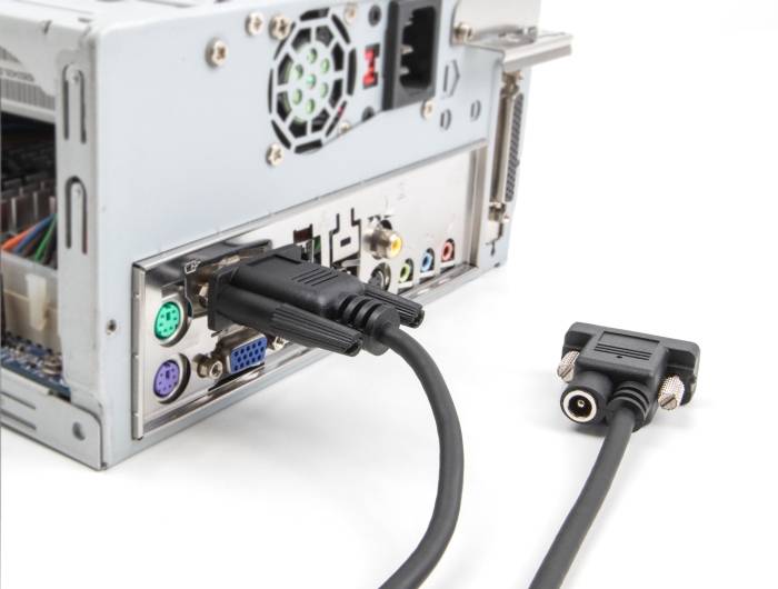 Ein schwarzes VGA-Kabel ist an einen Computer angeschlossen. Im Hintergrund sind weitere Anschlüsse und Kabel am Gehäuse sichtbar.
