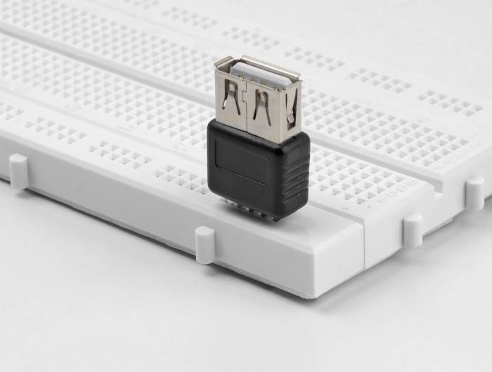 Ein schwarzer USB-Adapter steht auf einem weißen Steckbrett, das für Prototypen elektronischer Schaltungen verwendet wird.