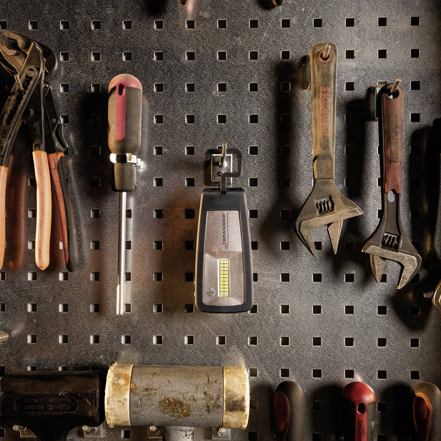 Eine Wand mit Werkzeugen, darunter Schraubenzieher, Spannungsmesser, Zangen und Schraubenschlüssel, die ordentlich in einem Raster angeordnet sind.