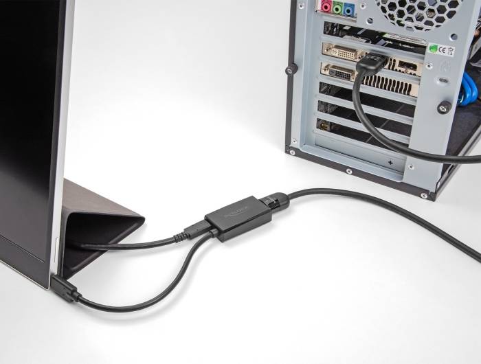 Ein Computermonitor ist mit einem Desktop-PC verbunden. Das Bild zeigt die Rückseite des PC-Gehäuses mit angeschlossenen Kabeln.