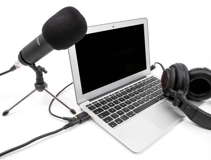 Laptop mit angeschlossenem Mikrofon und Kopfhörer, bereit für Audioaufnahme oder Podcasting.