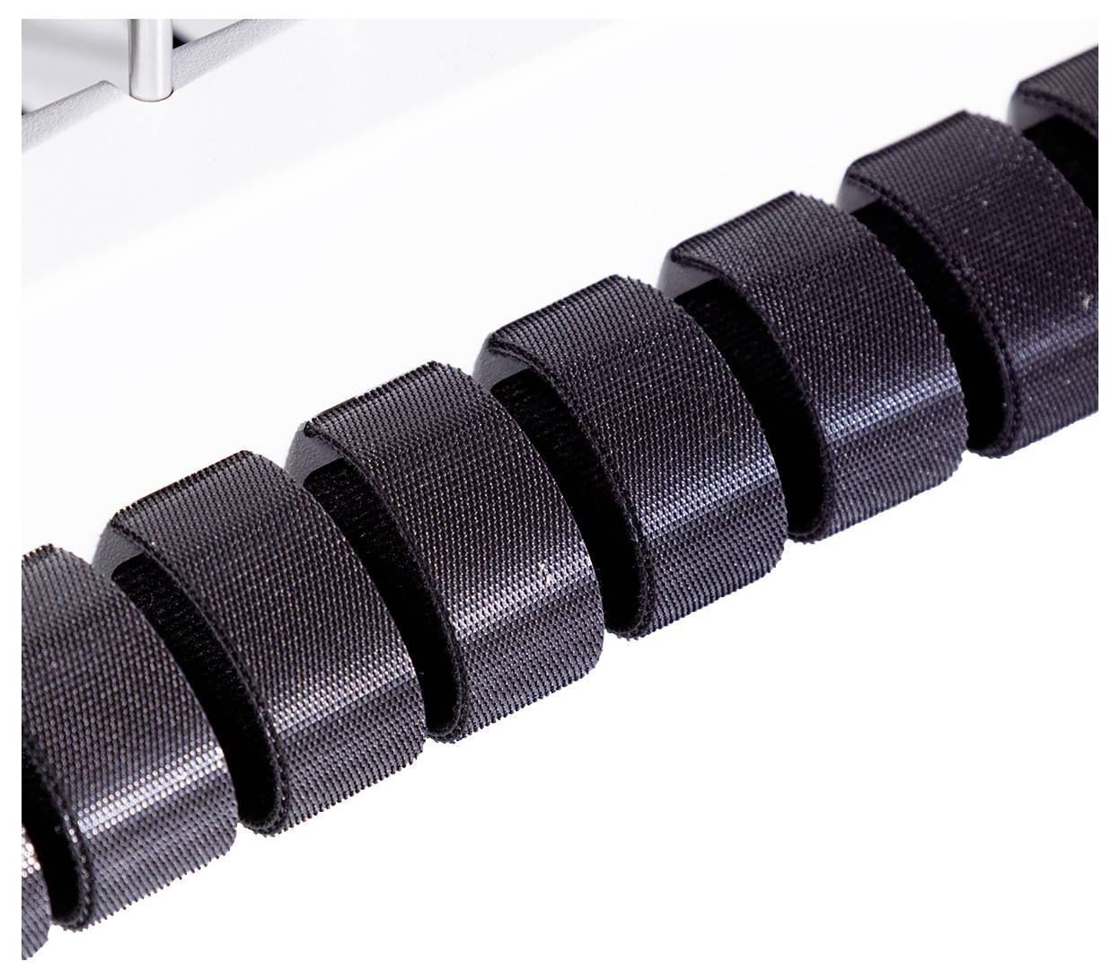 Eine Reihe schwarzer, gleichmäßig angeordneter, geriffelter Rollen in einer Maschine, möglicherweise ein Teil eines Förderbandsystems.