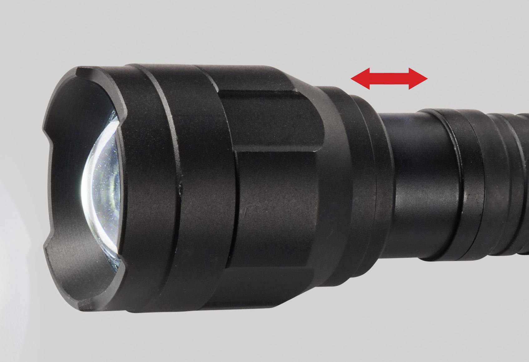 Schwarze Taschenlampe mit rotem Doppelpfeil zeigt Schiebebewegung für Fokusverstellung.