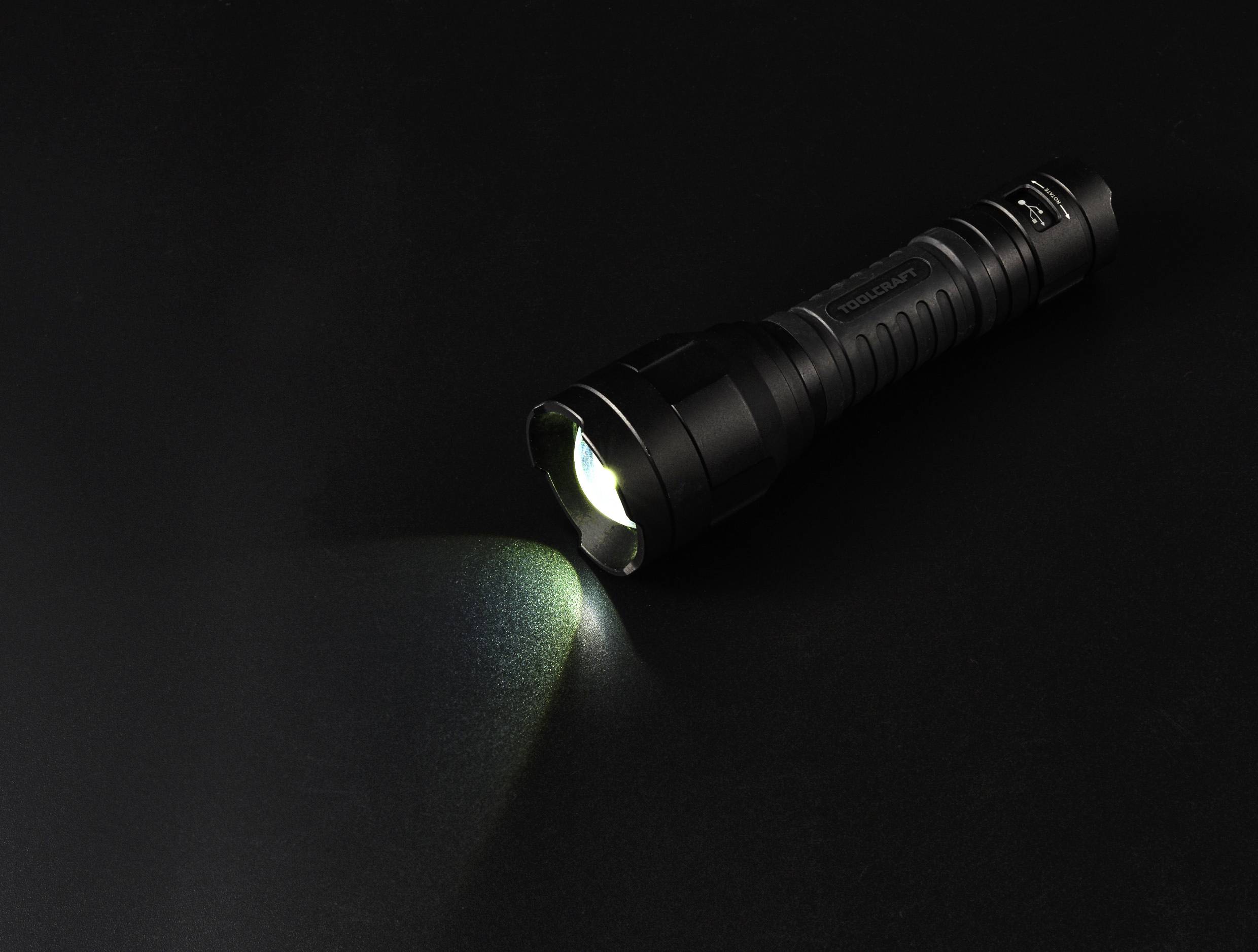 Taschenlampe strahlt Licht auf dunklem Hintergrund, symbolisiert Beleuchtung oder Suche in Dunkelheit.