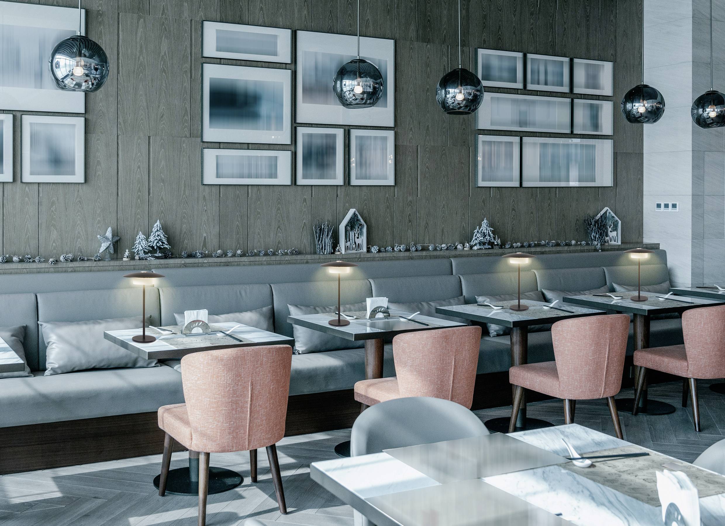 Modernes Restaurantinterieur mit rosa Stühlen, Holztischen und ambientem Licht. Wandkunst und sanfte Töne schaffen eine gemütliche Atmosphäre.