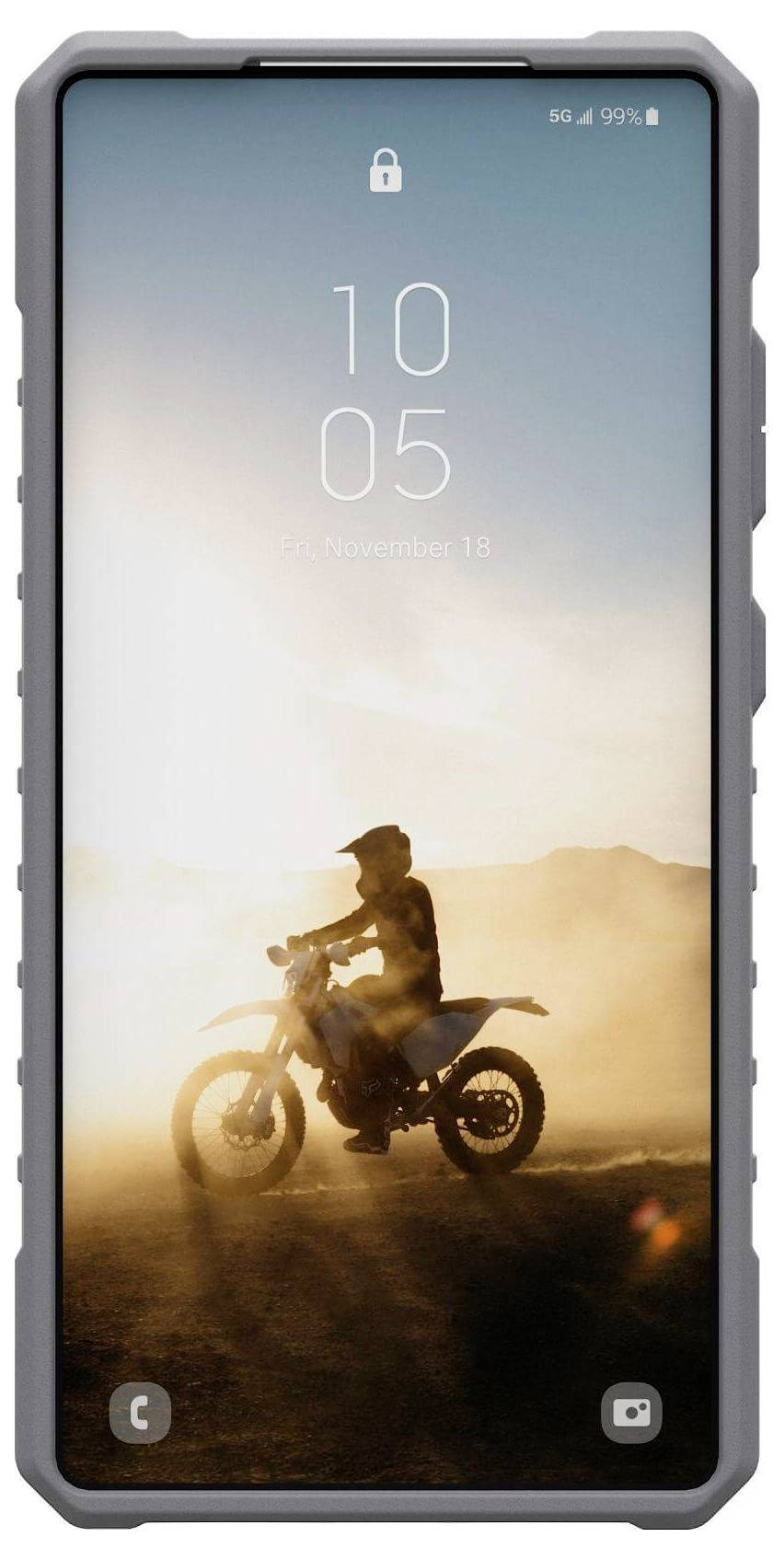 Ein Motorradfahrer fährt bei Sonnenuntergang durch eine Staubwolke in der Wüste. Der Himmel ist klar, und die Sonne ist tief am Horizont.