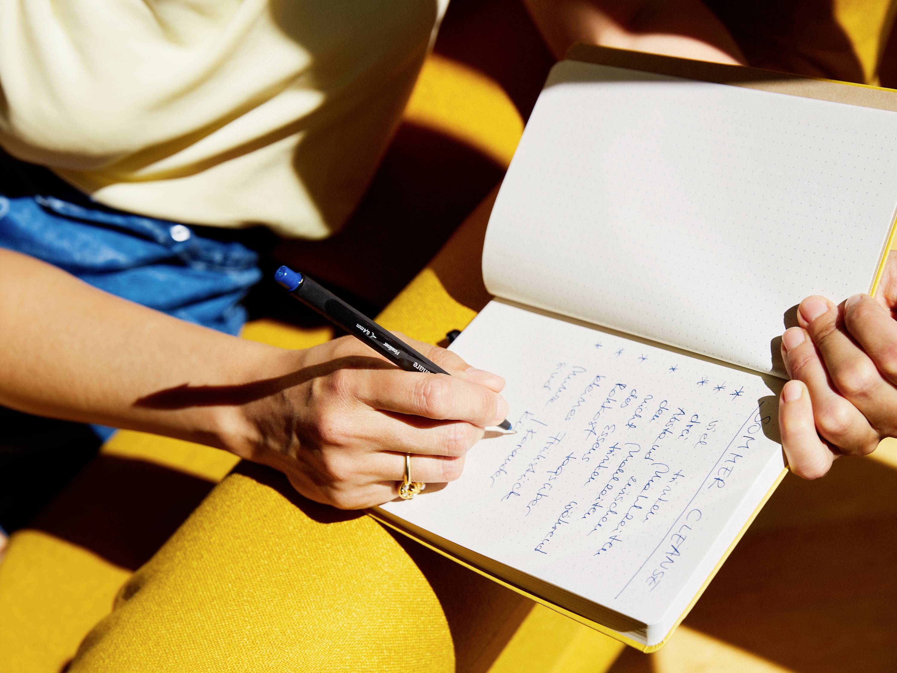 Eine Person schreibt Notizen in ein aufgeschlagenes Notizbuch mit Stift. Die Notizen scheinen sich auf das Thema 'Meeresklima' zu beziehen.