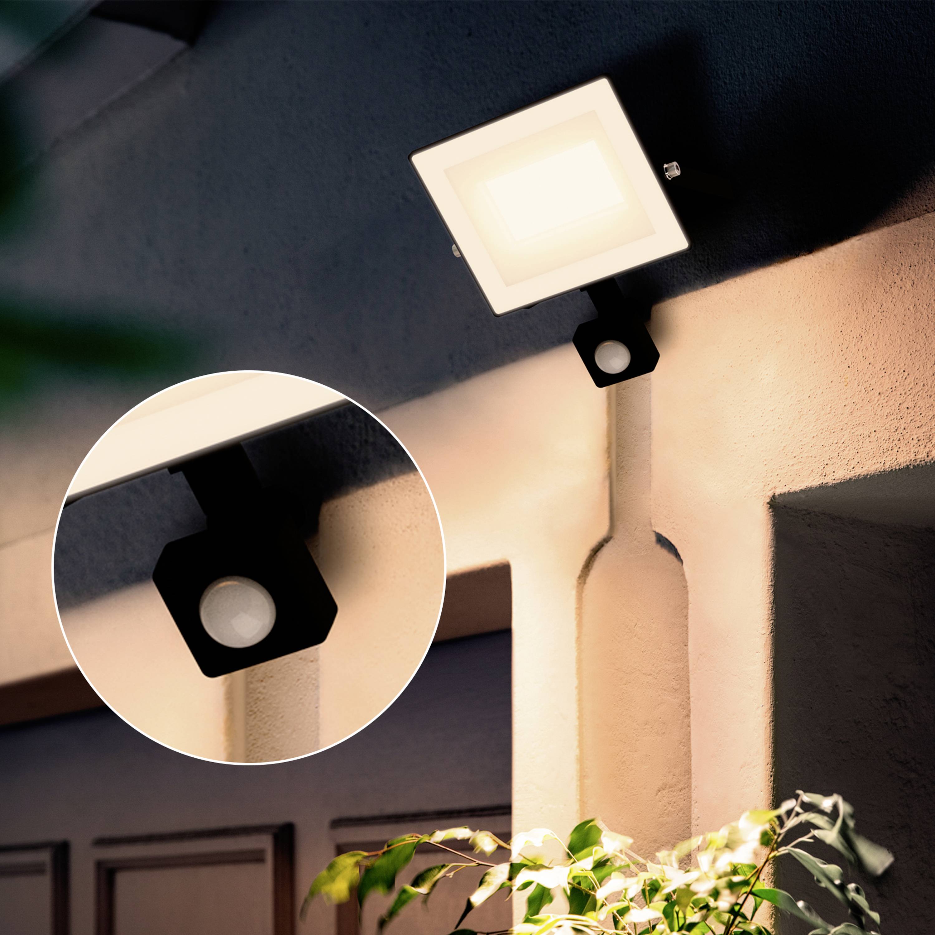 Außenleuchte an einer Hauswand, die einen hellen Bereich beleuchtet. Vergrößerter Einsatz zeigt die quadratische Form und das Licht der Leuchte.