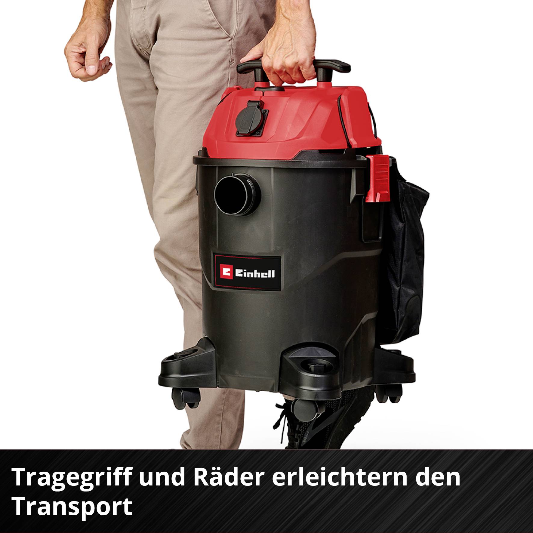 Ein Mann transportiert einen roten und schwarzen Staubsauger mit einem Tragegriff. Der Text lautet: 'Tragegriff und Räder erleichtern den Transport'.