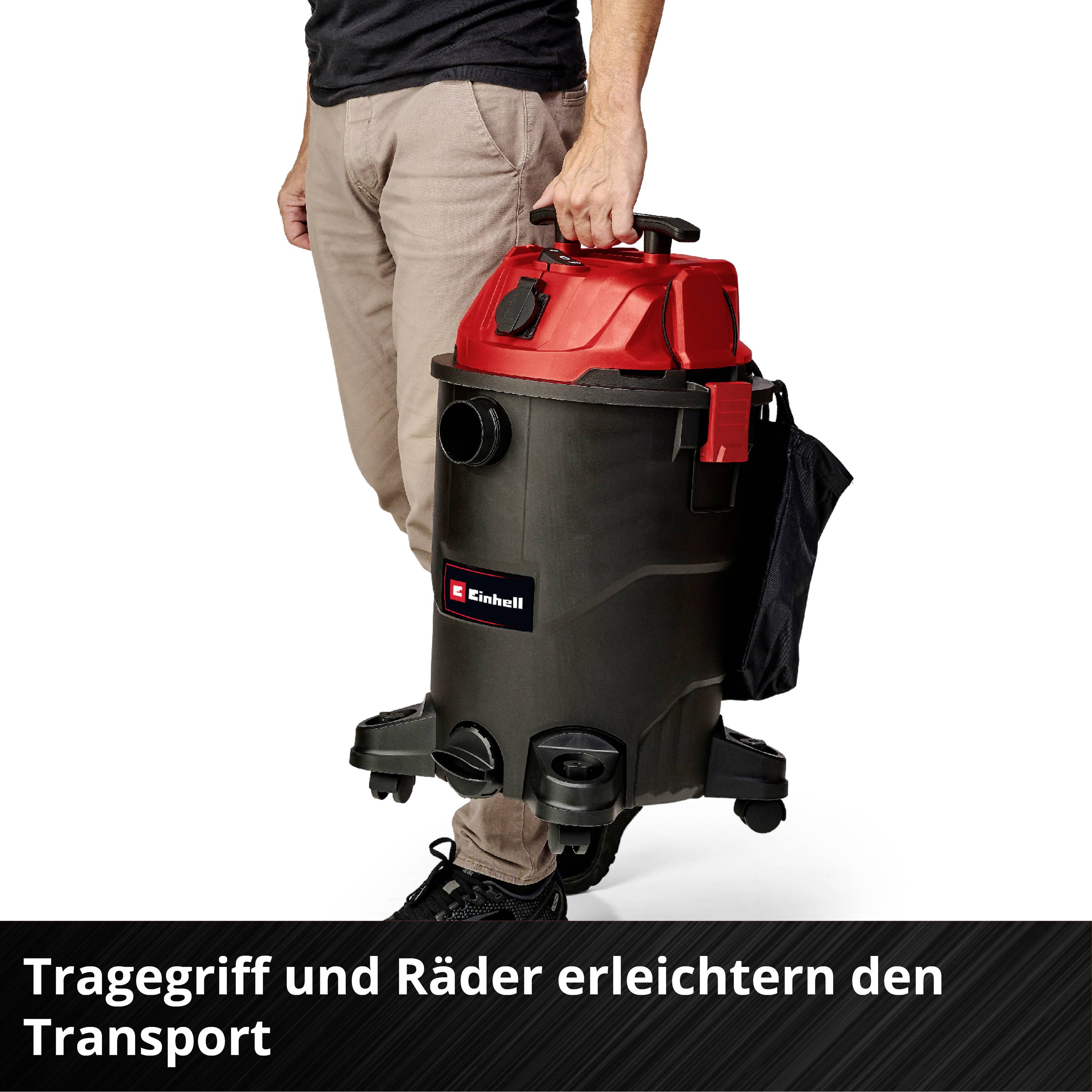 Mann hält Industriesauger mit rotem Deckel und integriertem Tragegriff. Text im Bild: Tragegriff und Räder erleichtern den Transport.