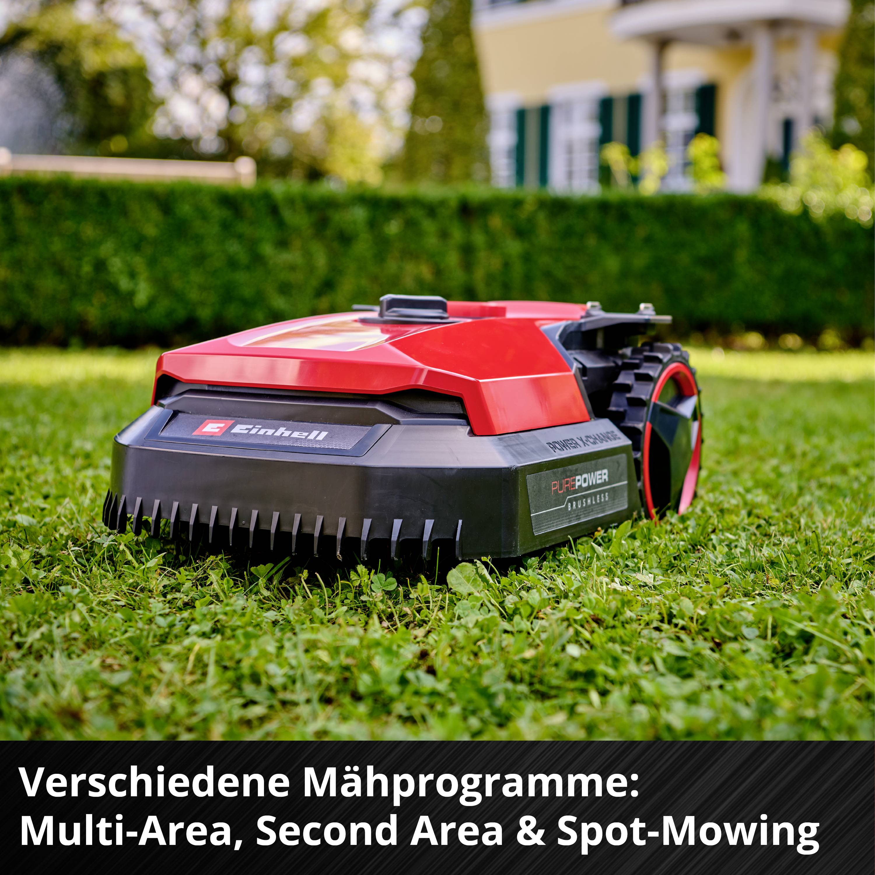 Ein roter Rasenmähroboter auf einem grünen Rasen vor einem Haus. Text: 'Verschiedene Mähprogramme: Multi-Area, Second Area & Spot-Mowing'.