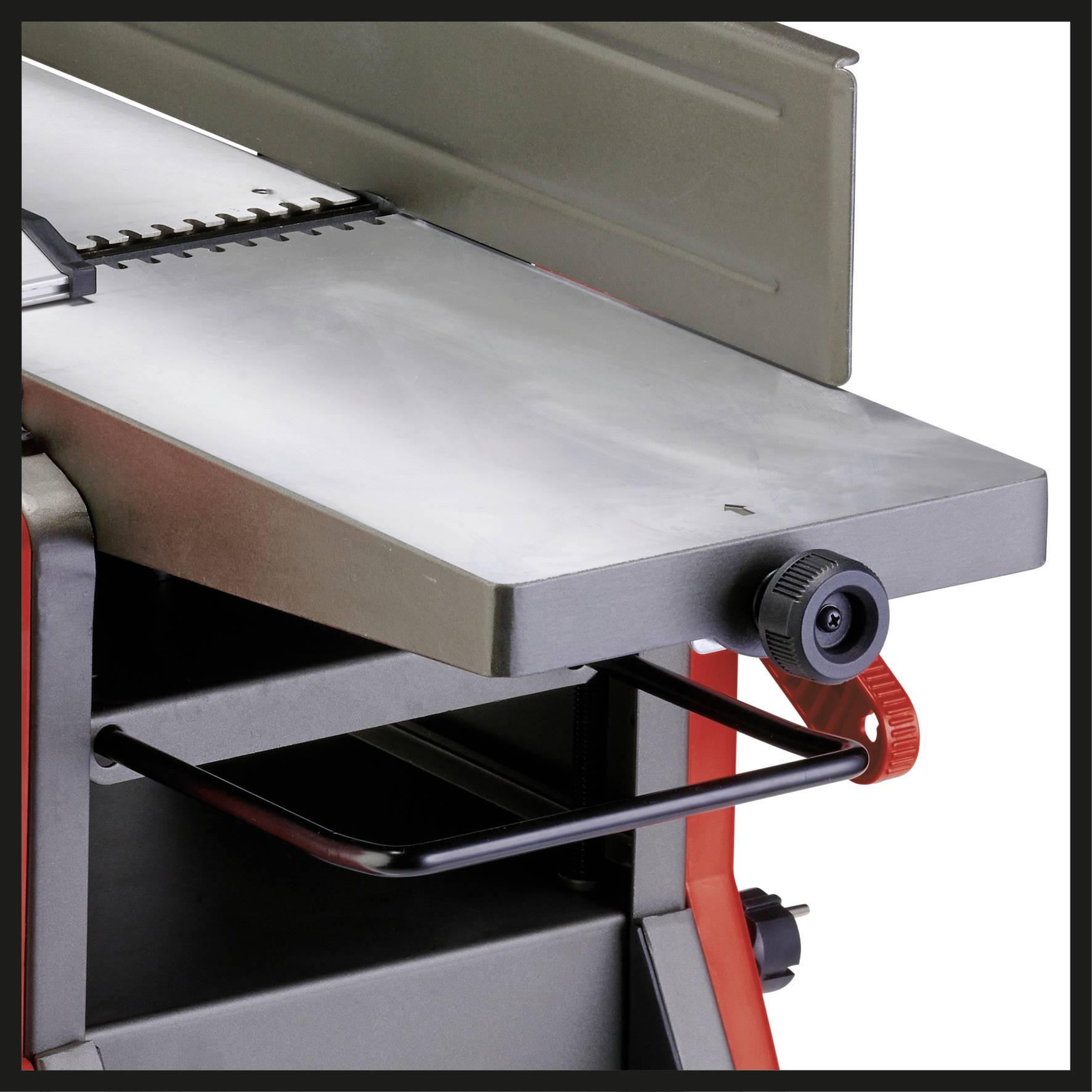 Eine Nahaufnahme eines Teils einer Metallmaschine mit einem schwarzen Einstellrad und einer roten Halterung.