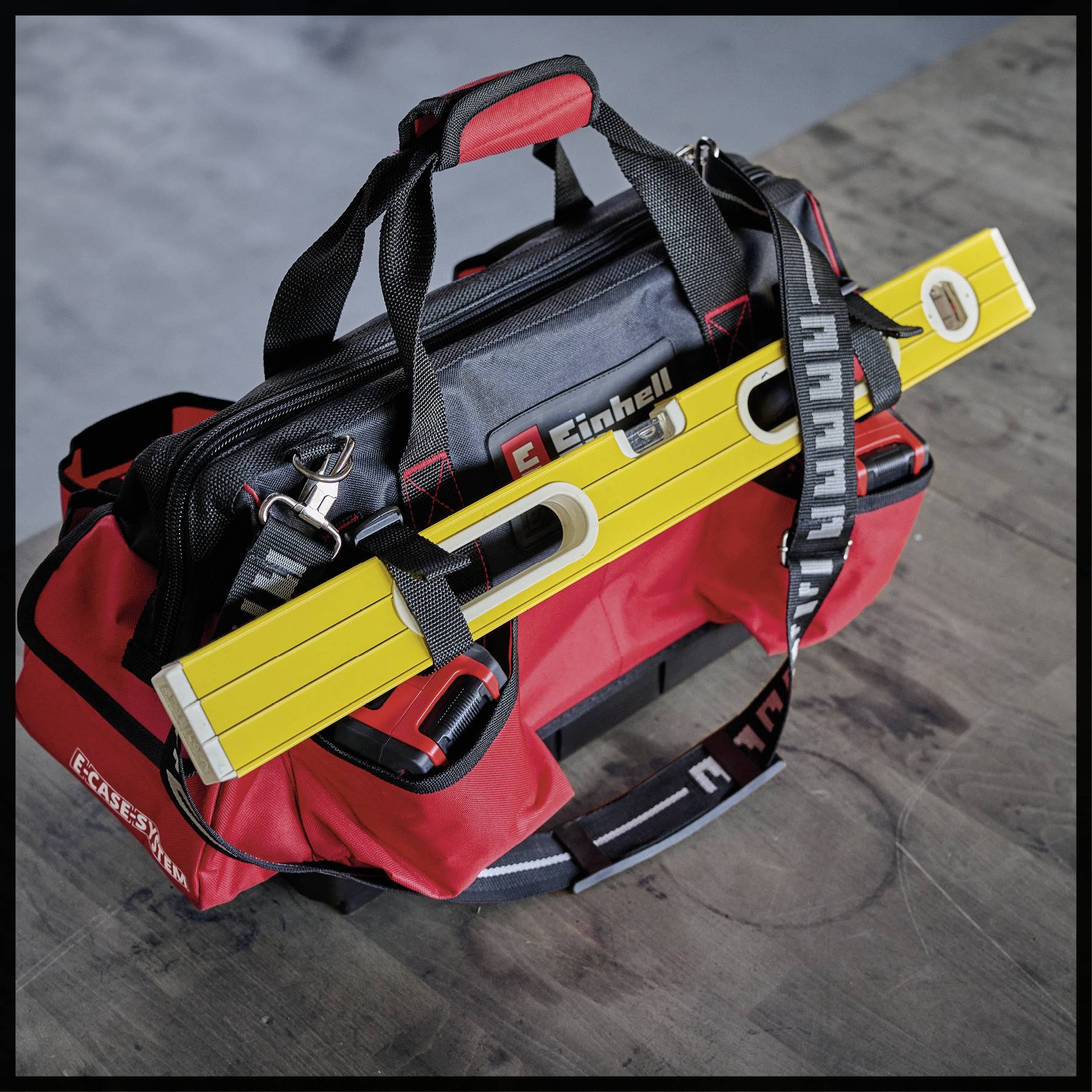 Eine rote Werkzeugtasche auf einem Tisch, gefüllt mit Werkzeugen wie Wasserwaage und Handwerkzeug, für Bauarbeiten oder Reparaturen.