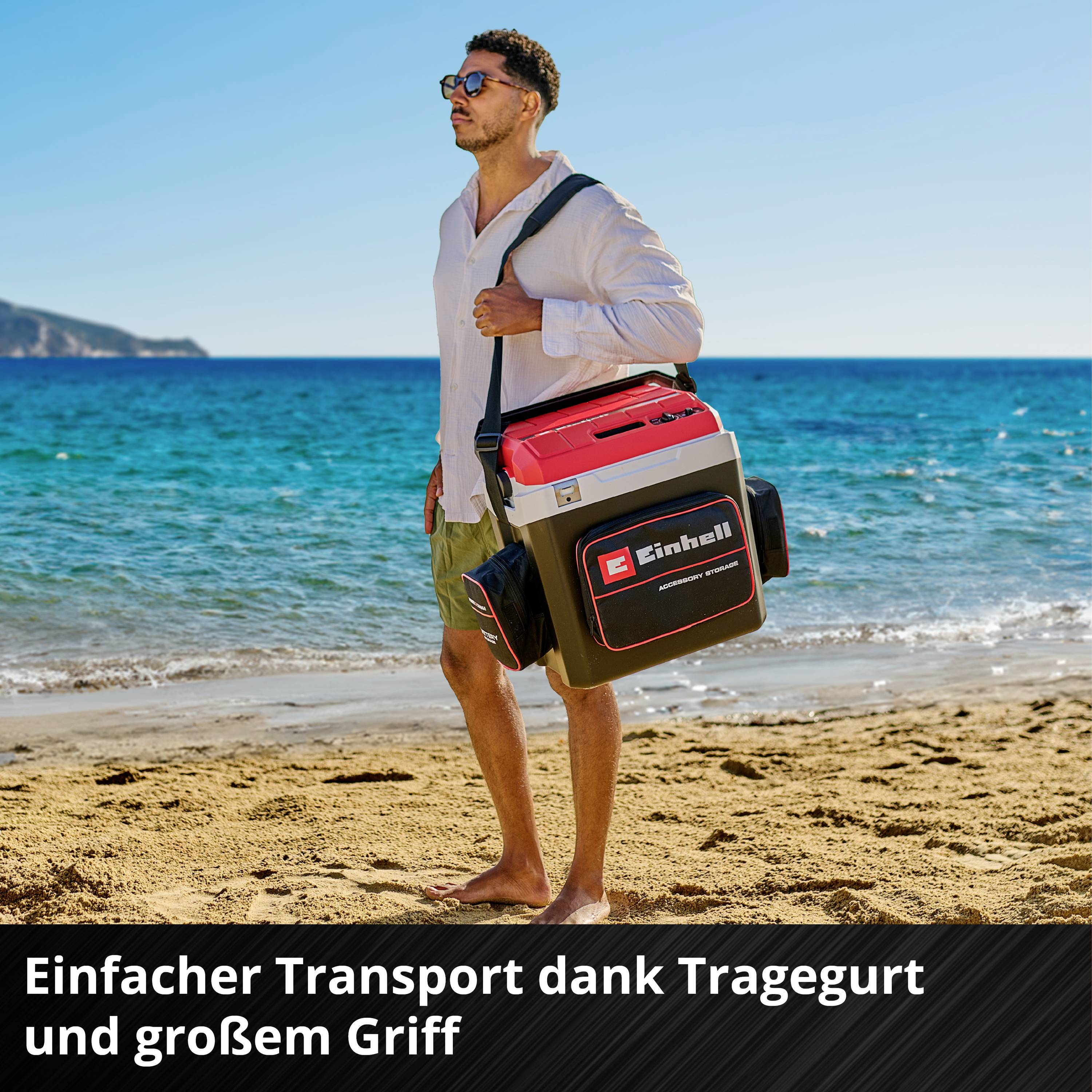 Ein Mann am Strand trägt eine Box mit Tragegurt. Darauf steht 'Einhell'. Text: 'Einfacher Transport dank Tragegurt und großer Griff'.