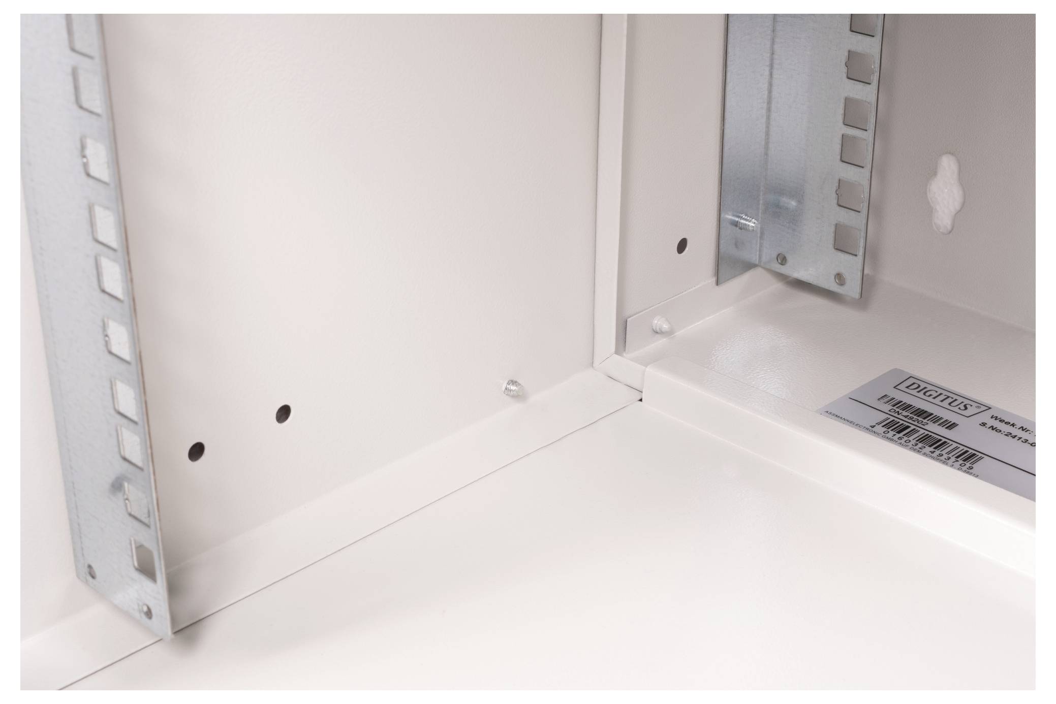 Innenansicht eines Metallgehäuses, die die Eckkonstruktion mit Nieten, zwei vertikalen Stützhalterungen und einem Herstelleretikett zeigt.