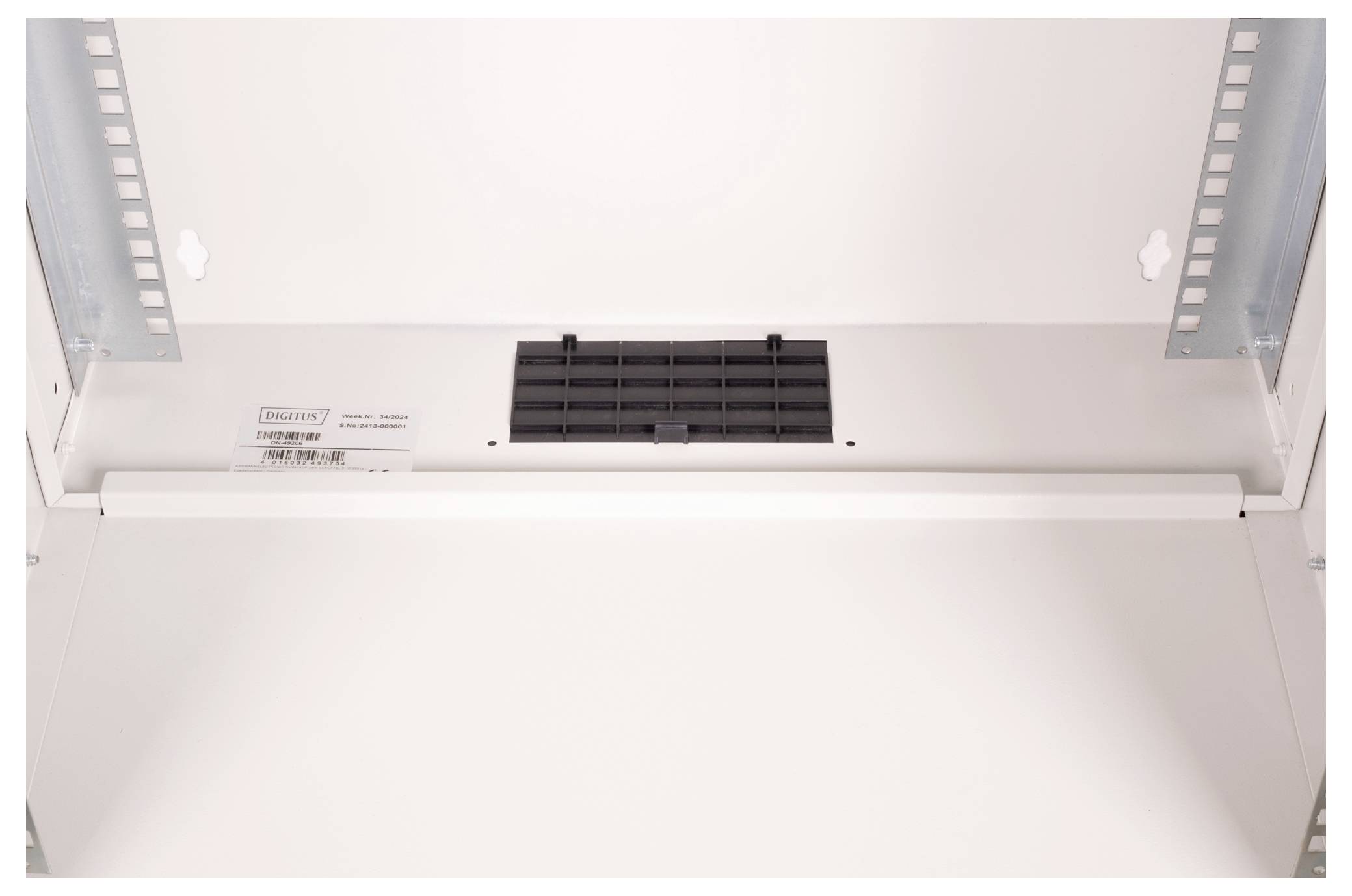 Inneres eines leeren weißen Elektroverteilerkastens mit einem Lüftungsgitter oben und einem Türmechanismus mit Scharnier.