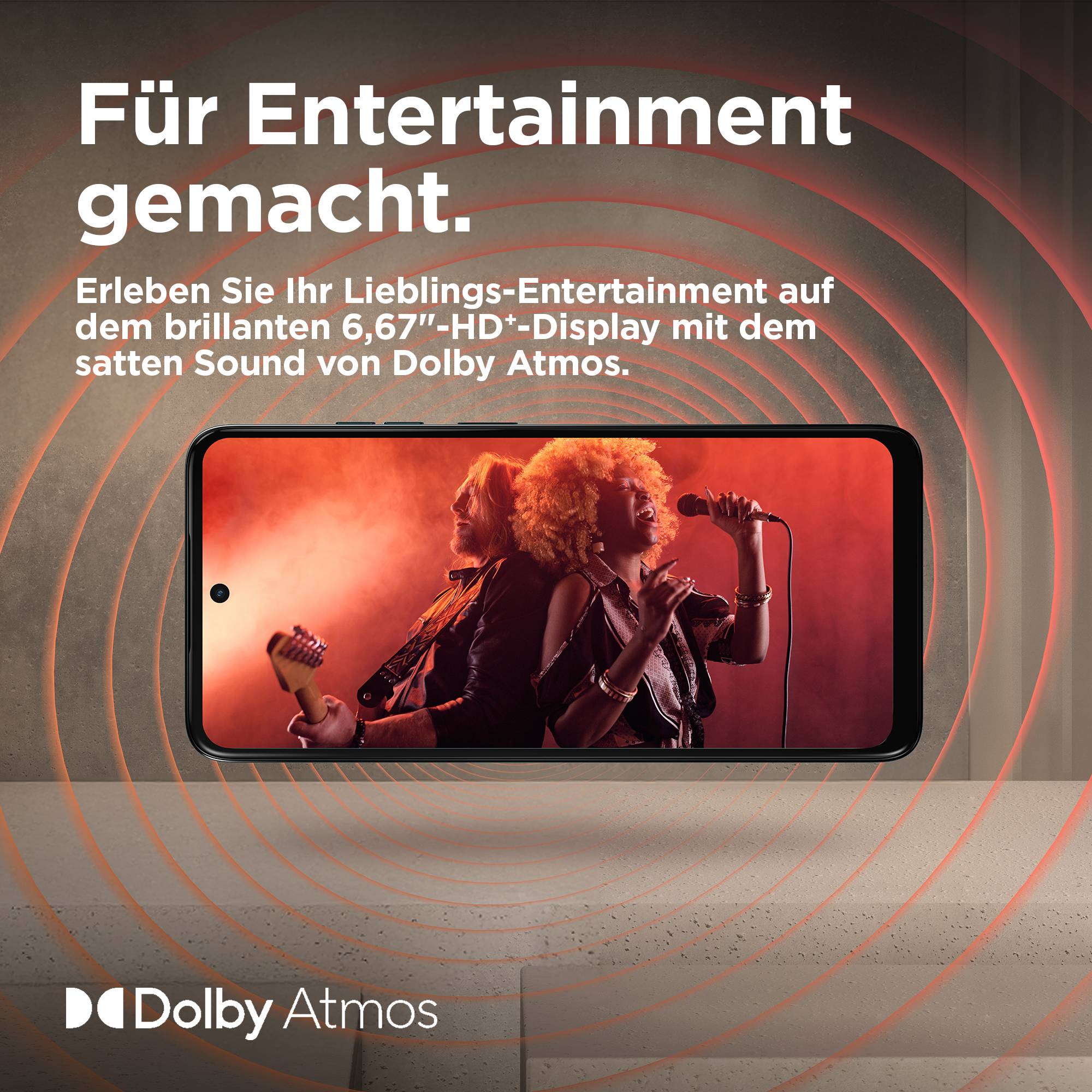 Ein Smartphone zeigt ein Konzertvideo. Darüber steht der Text 'Für Entertainment gemacht', darunter 'Dolby Atmos'.