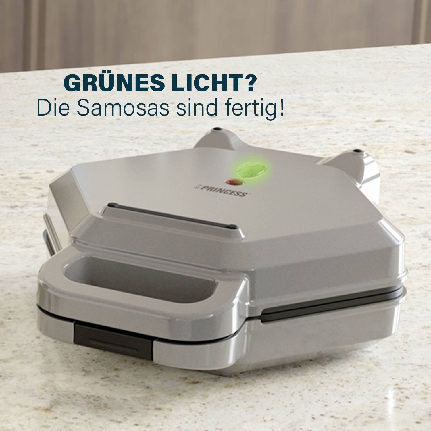 Ein silberner Samosa-Maker mit grünem Licht steht auf einer Arbeitsfläche. Text darüber: 'Grünes Licht? Die Samosas sind fertig!'
