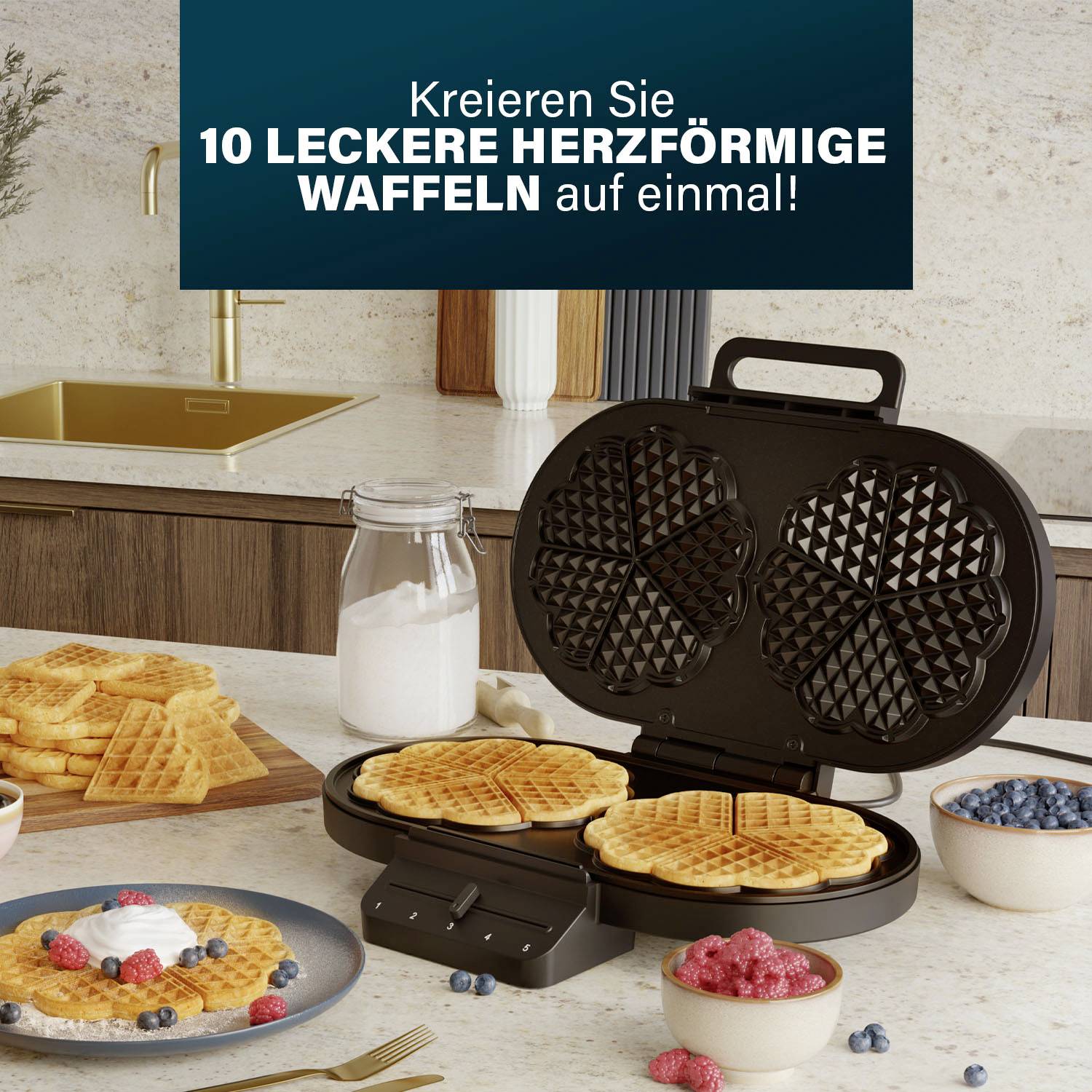 Ein Waffeleisen in einer Küche backt herzförmige Waffeln. Daneben stehen frische Waffeln, Beeren, Sahne und Milch.