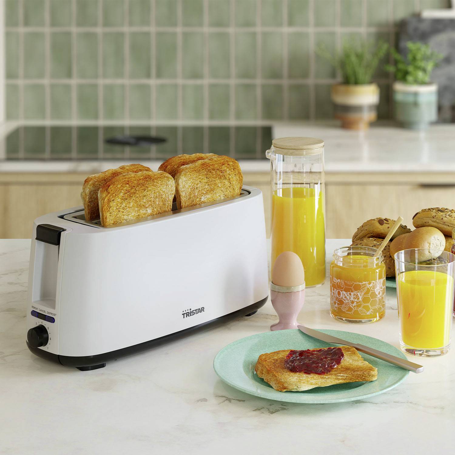 Ein Toaster mit zwei Scheiben Toast. Daneben stehen ein Glas Orangensaft, ein Honigglas, eine kleine Vase und Marmeladentoast auf einem Teller.