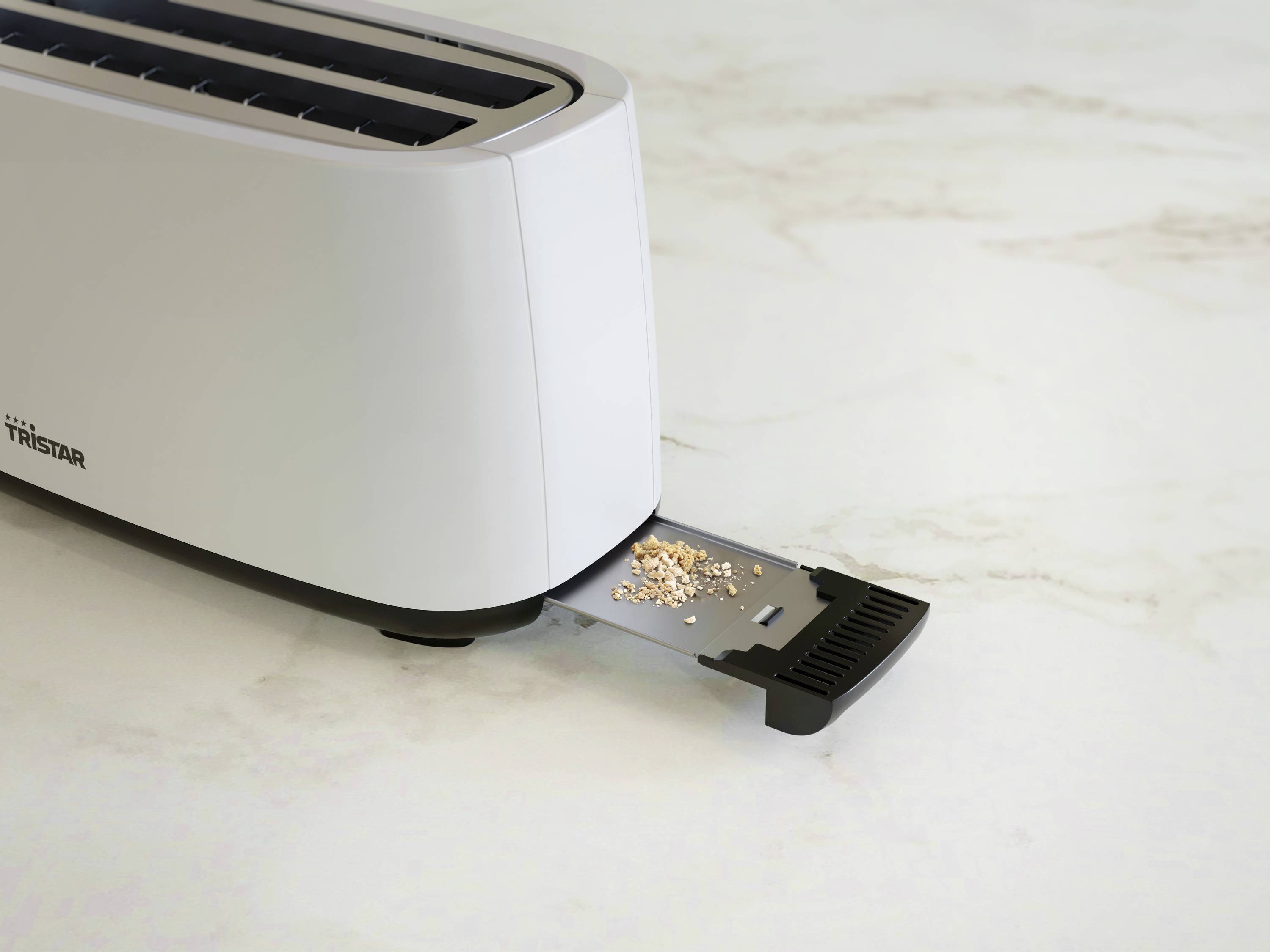 Ein Toaster steht auf einer Arbeitsplatte mit herausgezogener Krümelschublade. Einige Krümel liegen auf der Schublade.