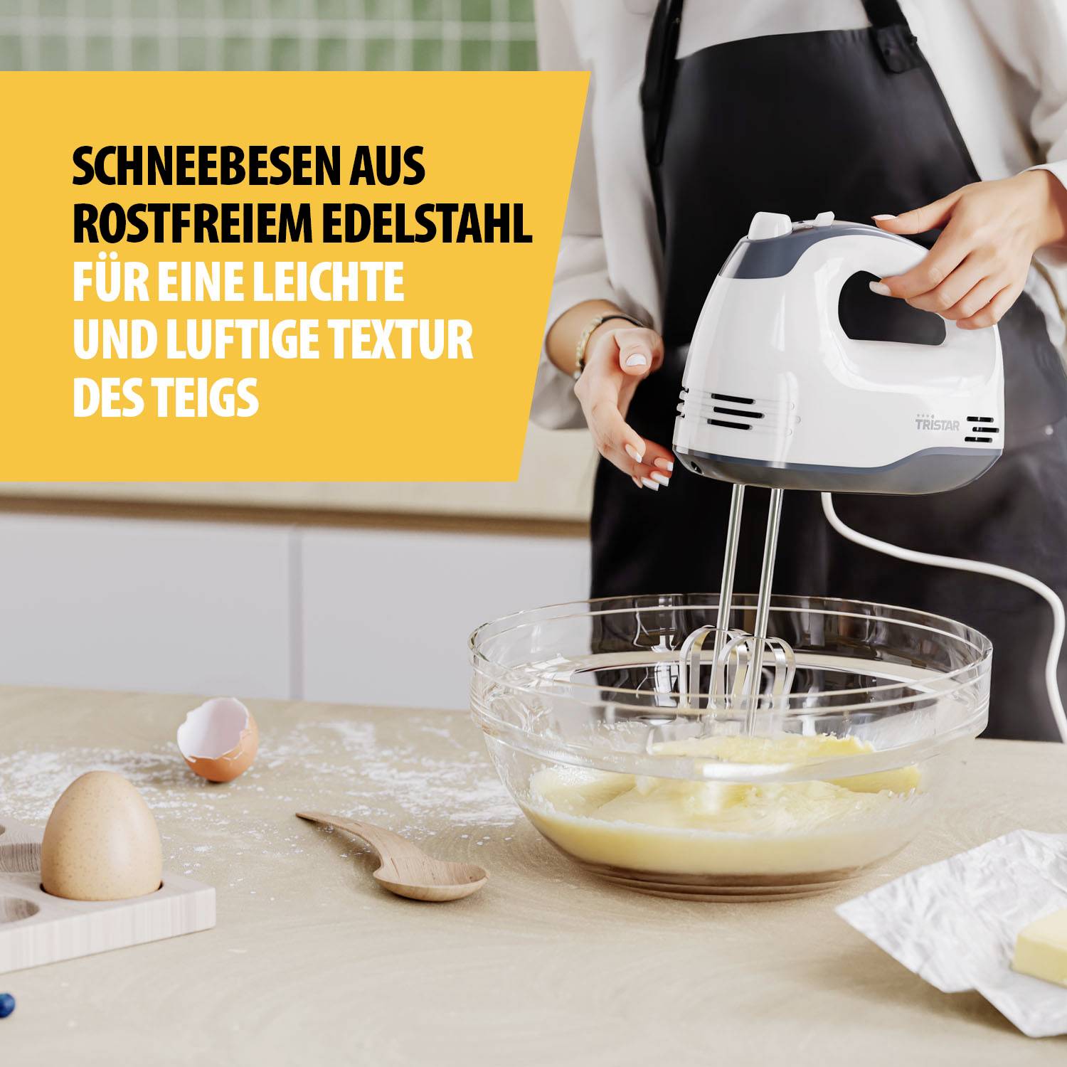 Eine Person rührt mit einem Handmixer Teig in einer Schüssel. Text: 'Schneebesen Edelstahl für luftige Textur des Teigs'.
