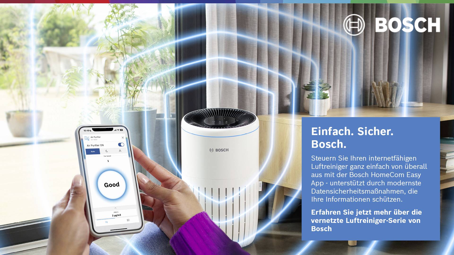 Am Tisch sitzende Person benutzt die Bosch HomeCom Easy App auf einem Smartphone, um einen Luftreiniger zu steuern. Text: Einfach. Sicher. Bosch.