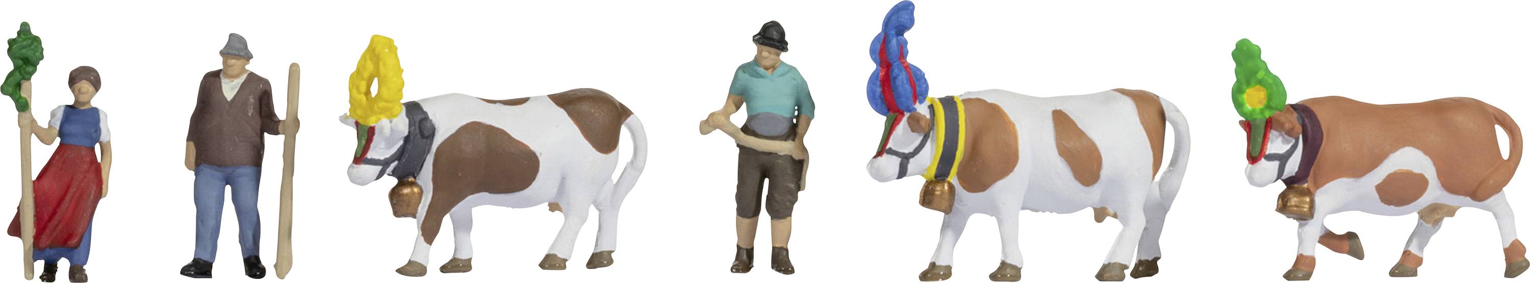 Miniaturfiguren von zwei Menschen in traditioneller Kleidung mit drei Kühen, die bunte Kopfbedeckungen und Kuhglocken tragen.