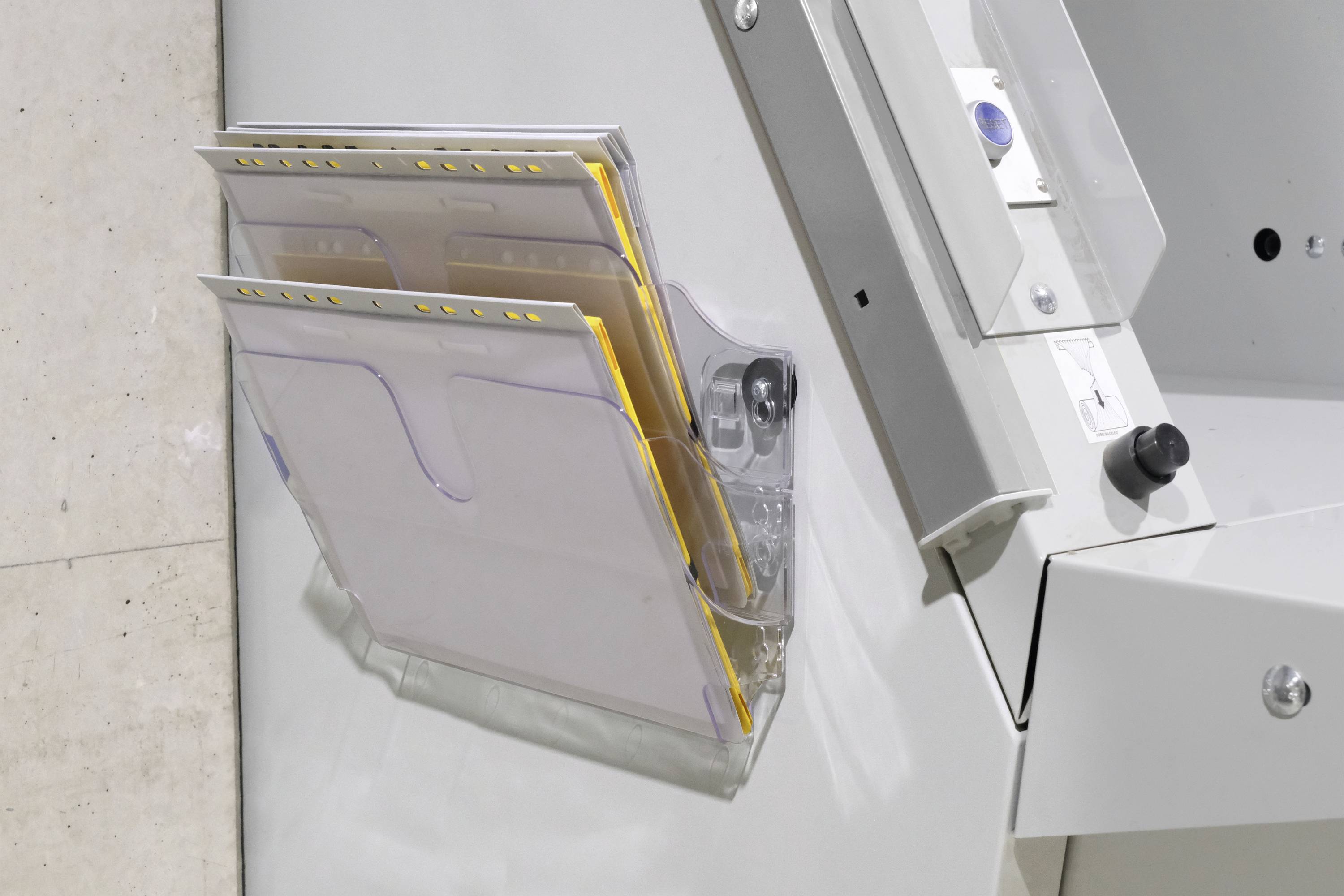 Ein grauer Metallbehälter mit mehreren Papierfächern ist an der Wand montiert. Die Fächer sind teilweise gefüllt mit Dokumenten.