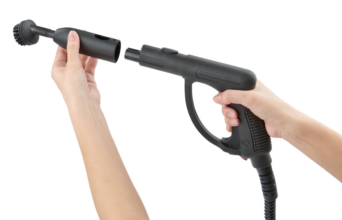 Eine Person hält einen Dampfreiniger in der Hand und montiert eine Bürstendüse, bereit zur Reinigung.