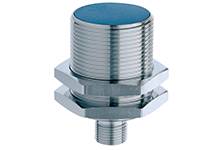 Ein zylindrischer, metallischer Induktionssensor mit geripptem Gehäuse und einem Gewindeanschluss, zur automatisierten Erkennung von Objekten.