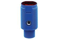 Ein blauer zylindrischer Sensor mit gerippter Oberfläche und roter Linse, verwendet in Industrieanwendungen zur Objekterkennung.
