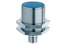 Metallischer, zylindrischer Sensor in Nahaufnahme, mit einem Gewinde in der Mitte und einem Anschluss an der Unterseite.