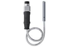 Ein kabelgebundener elektrischer Sensor mit einem zylindrischen Metallgehäuse und einem schwarzen Stecker, der Kabel verbunden ist.