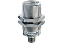 Metallsensor in zylindrischer Form, befestigt mit Sechskantmutter. Gehäuse aus Edelstahl beschriftet mit 'CONTRINEX DW-AD-7030-002'.