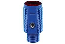 Ein blauer zylindrischer Sensor mit roter Linse oben und einer schwarzen Anschlussöffnung an der Seite.