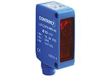 Ein rechteckiger blauer Sensor mit Aufschrift 'Contrinex', sichtbarem Sichtfenster und Anschluss an der Unterseite. Verwendet zur Objekterkennung.