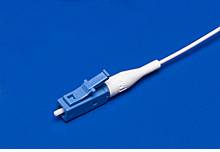 Ein blau-weißer Glasfaserstecker liegt auf einem blauen Hintergrund.
