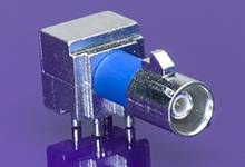 Ein silber-blauer Koaxialstecker mit rechteckigem Metallgehäuse auf einem lila Hintergrund.