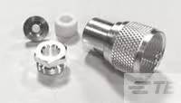Ein Koaxialstecker-Set auf einem Tisch, bestehend aus einem Metallstecker und vier kleinen Komponenten, inklusive einer Sechskantmutter.