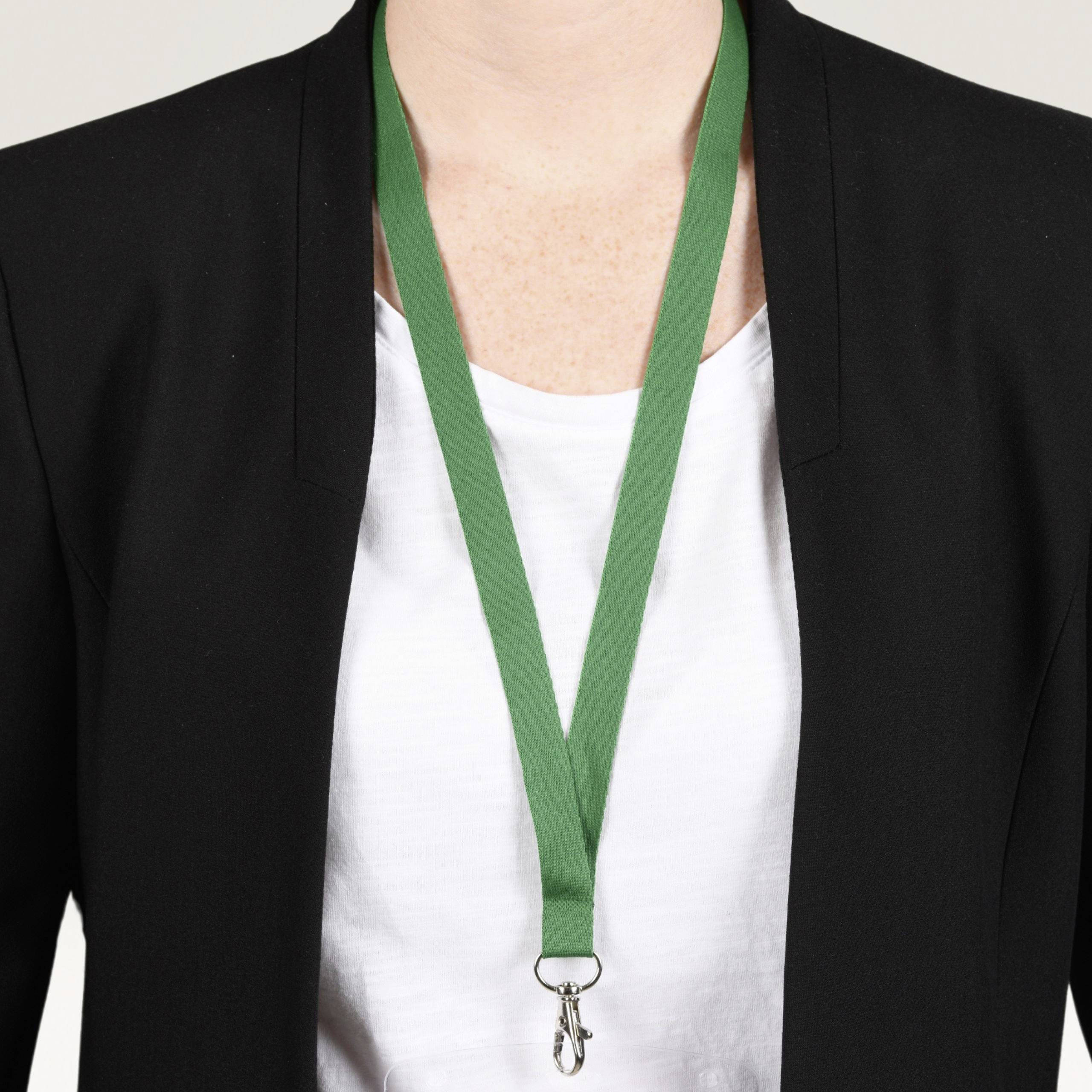 Eine Person trägt ein weißes Hemd und einen schwarzen Blazer. Um den Hals hängt ein grünes Band mit einem Schlüssel.