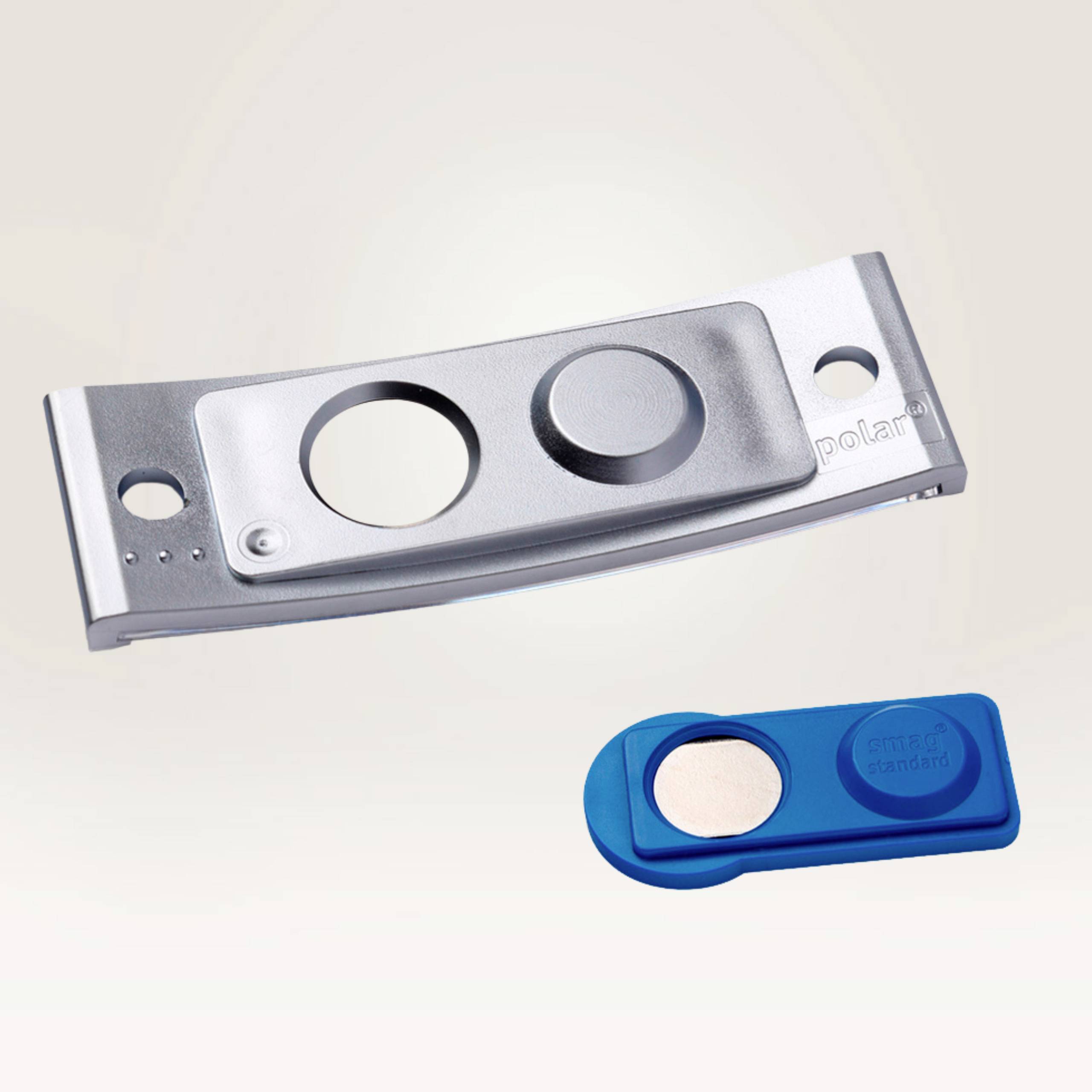 Zwei abgerundete Objekte zur Pulsmessung in Silber und Blau. Oben: Metallrahmen mit zwei Aussparungen. Unten: Blaues Gummigehäuse mit silberner Kappe.