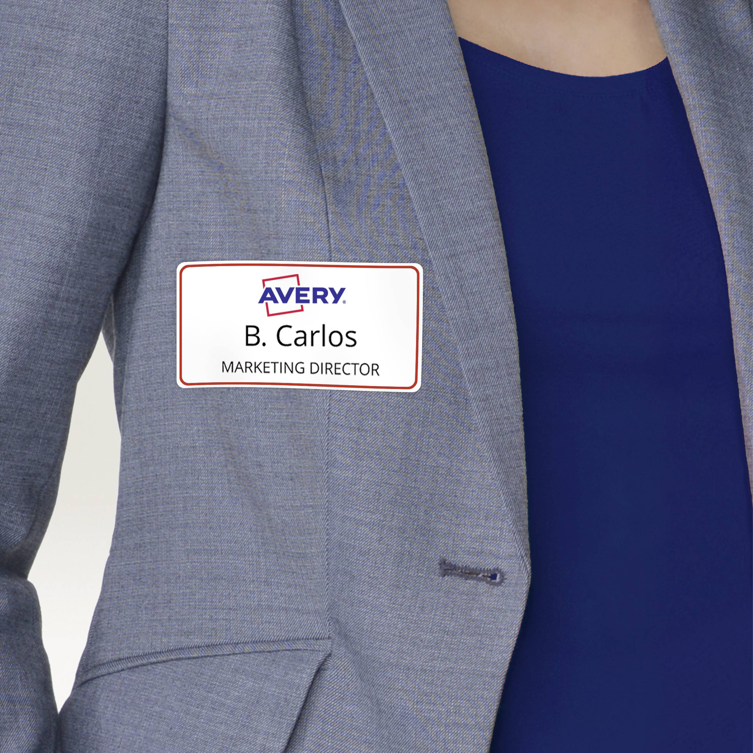 Eine Person trägt ein Namensschild mit der Aufschrift 'B. Carlos, Marketing Director' auf einem grauen Blazer.