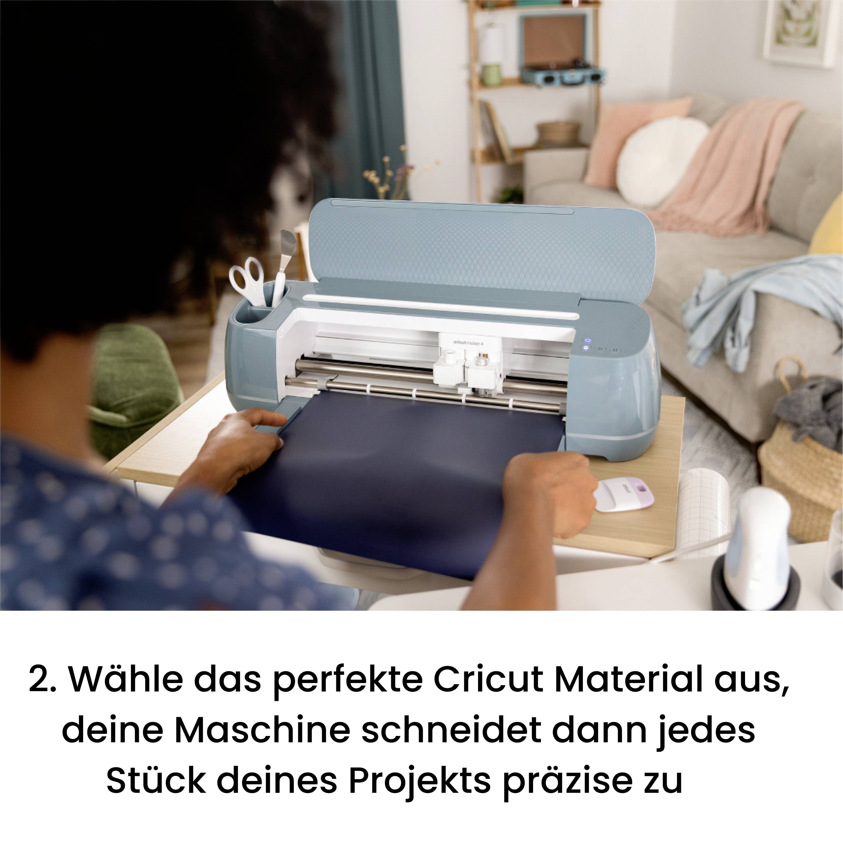 Person legt Material in Cricut-Maschine ein, um es präzise schneiden zu lassen. Im Hintergrund gemütliches Wohnzimmer.