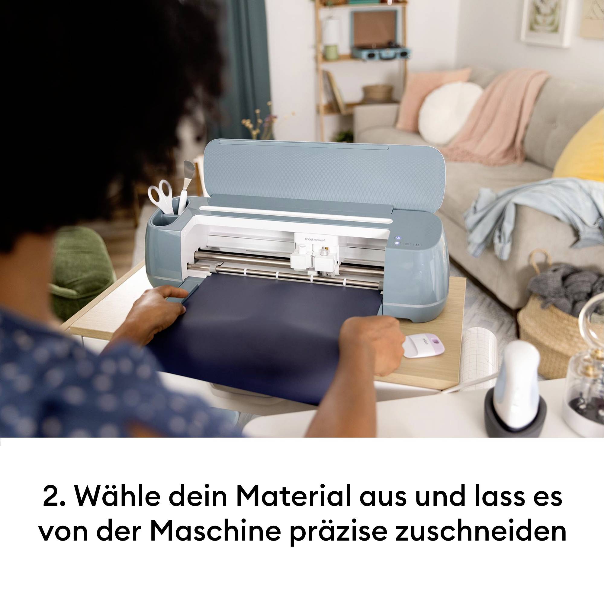 Eine Person legt ein Material in eine Schneidemaschine ein, um es präzise zuzuschneiden. Im Hintergrund ist ein Sofa zu sehen.